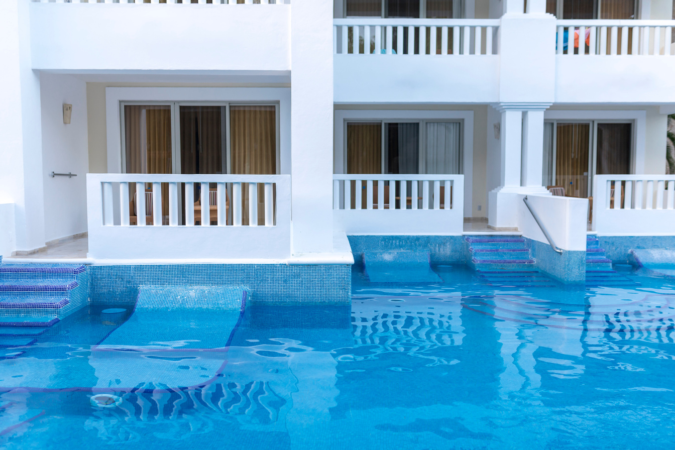 Low view perspective of a luxury tropical all inclusive hotel with balconys and a swim up pool in a hotel in Mexico